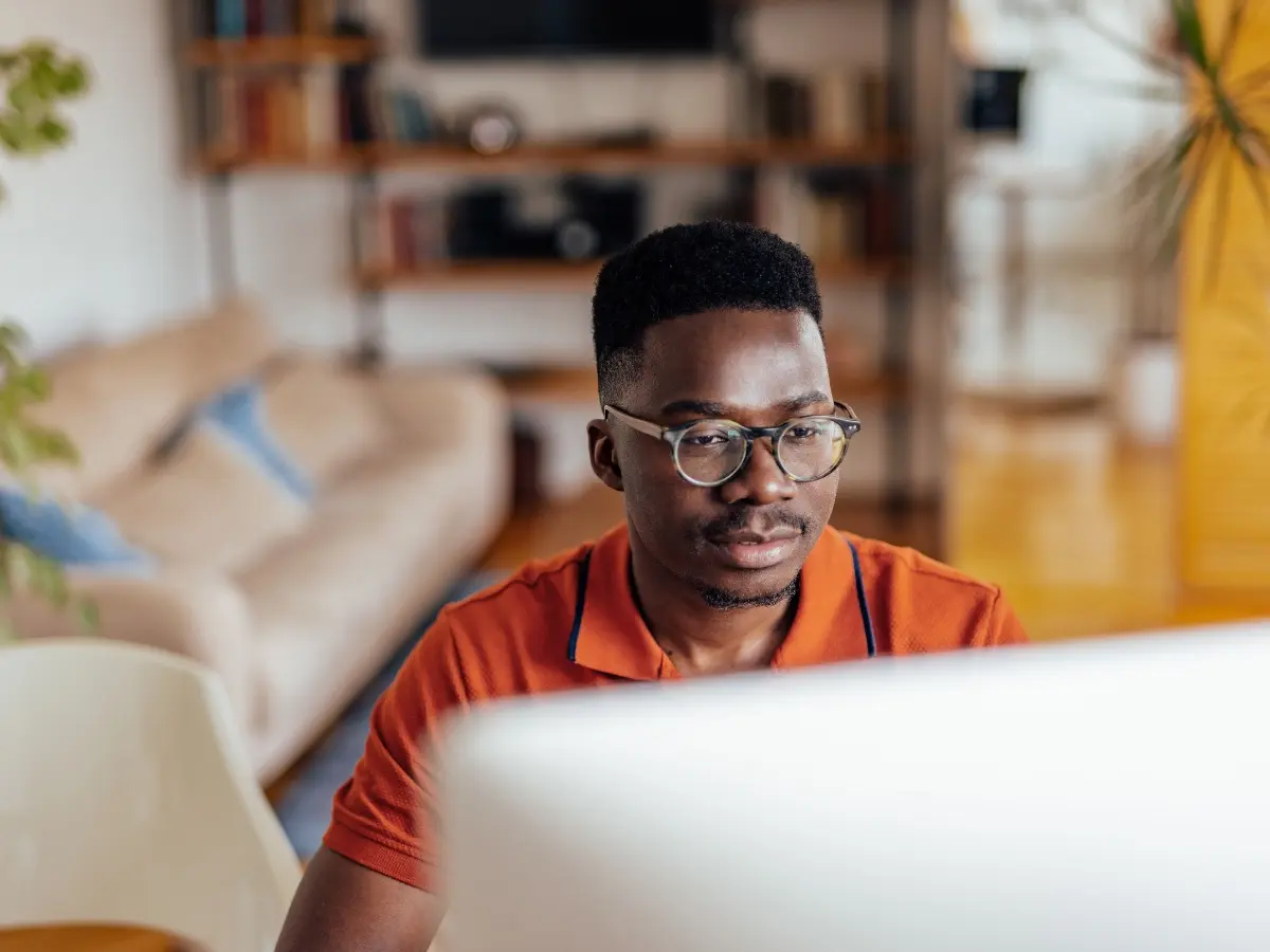 A man sitting at a desktop computer in his living room