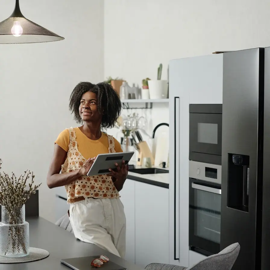 A homeowner reviewing her kitchen appliances with a tablet in hand