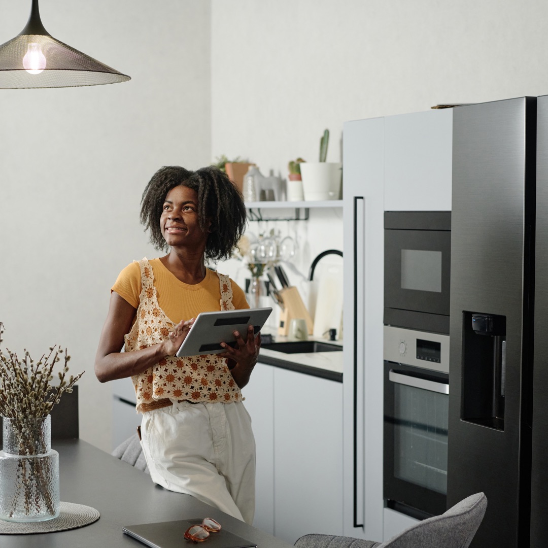 A homeowner reviewing her kitchen appliances with a tablet in hand